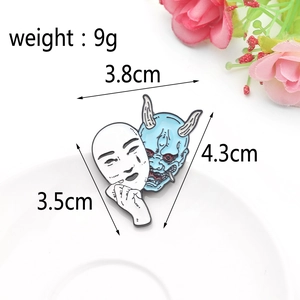 Macro view of white Noh and blue Hannya enamel pins with size and weight dimensions