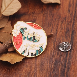 Macro detail of wave enamel pin on wood with gold outlines and sunset imagery