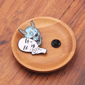 Japanese Oni and Noh mask enamel pin on a wooden display tray for backpack decor
