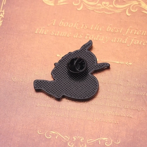 Close-up of the back of the black enamel pin with a secure butterfly clutch on a book