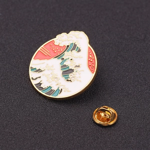 Macro shot of circular enamel ocean wave brooch with gold plating and butterfly clutch back