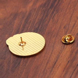 Macro view of gold metal pin back with textured surface and butterfly clutch closure