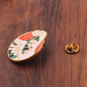 Cartoon enamel wave brooch with golden metal base and red sun pin on wood background
