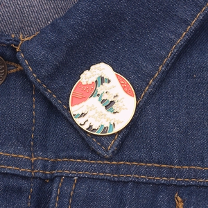 Detailed close-up of a Great Wave enamel pin on a blue denim jacket collar