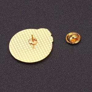 Back view of round enamel pin badge with gold butterfly clutch on textured background