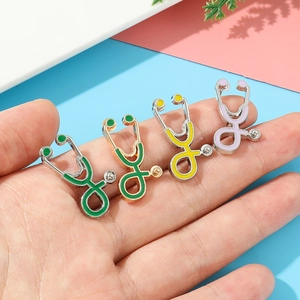 Gros plan de quatre broches stéthoscope en émail coloré tenues en main pour la taille