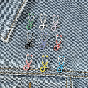 Gros plan de neuf épingles en émail stéthoscope colorées sur tissu denim bleu
