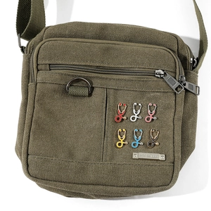 Détail de broches stéthoscope en émail coloré en six couleurs sur un sac en toile vert