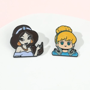 Detail shot of Jasmine and Cinderella enamel pins on a soft pink background