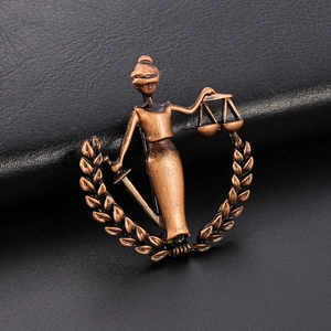 Macro detail of Lady Justice bronze brooch with scales and sword on black leather background