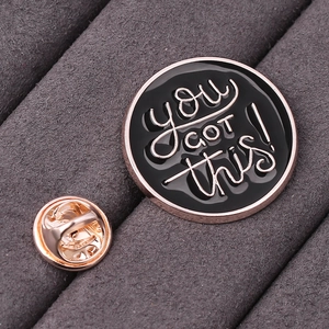 Dettaglio della spilla smaltata rotonda con bordo oro rosa e scritta motivazionale 'YOU GOT THIS!'