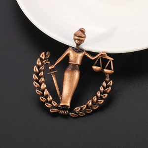 Detail of antique bronze Libra pin featuring Lady Justice with scales and sword
