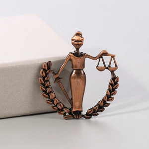 Detail of vintage copper Lady Justice brooch with scales and sword in laurel wreath