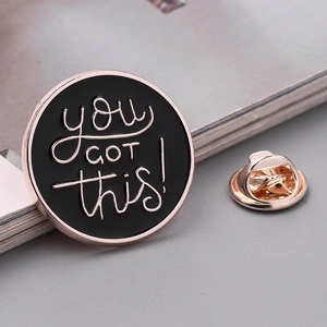 Macro di una spilla rotonda in smalto con scritta 'you GOT this!' e chiusura a farfalla