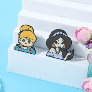 Detailed view of Cinderella and Jasmine cartoon enamel pins on a white display stand