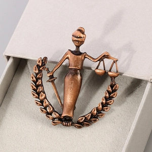 Antique copper Libra metal brooch featuring Lady Justice with scales and sword on velvet