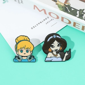 Detailed macro view of Cinderella and Jasmine enamel pins on a modern magazine