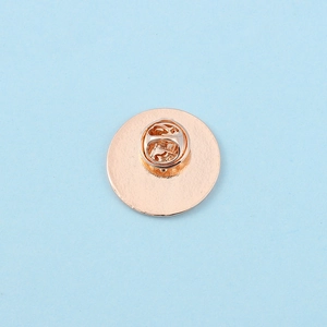 Dettaglio del retro della spilla circolare in oro rosa con chiusura a farfalla sicura
