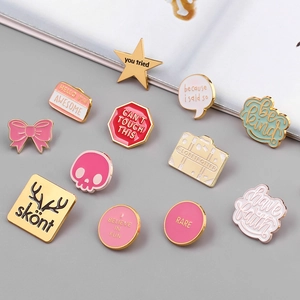 Flat lay of diverse enamel pins with motivational quotes and gold metal plating