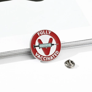 Detailed close-up of a Fully Vaccinated round enamel lapel pin with syringe design