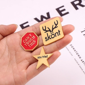 Three custom enamel lapel pins with unique geometric shapes and English typography