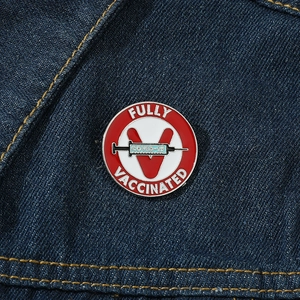Zinc alloy COVID-19 vaccine badge with Fully Vaccinated text pinned on denim fabric