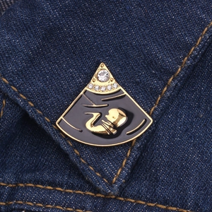 Macrofoto van foetus echografie emaille speld met goud metaal en stras op denim stof