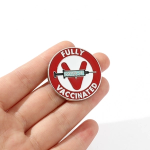 Macro shot of circular enamel COVID-19 vaccine badge with Fully Vaccinated text in hand