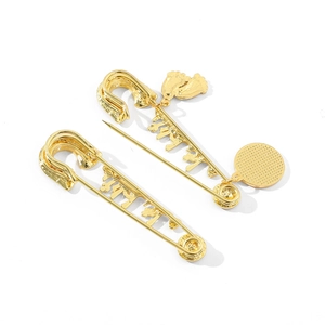 Detail of gold safety pins with Arabic calligraphy and tiny footprint charms