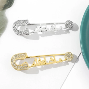 Macro view of gold and silver safety pin brooches with Arabic calligraphy and crystals