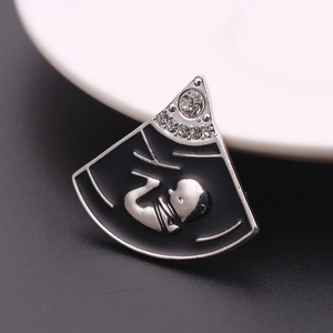 Macro-opname van zilveren waaiervormige broche met baby-echografie email en strass
