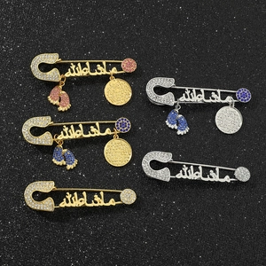 Detail of Arabic Mashallah brooches with rhinestone baby feet on black background