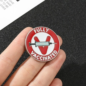 Fully Vaccinated metal pin featuring a red V and syringe on a black textured backdrop
