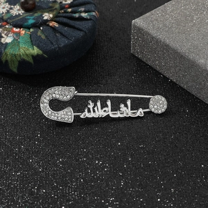 Macro detail of silver brooch with Arabic Mashallah calligraphy and sparkling crystals