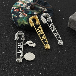 Detailed macro view of gold and silver letter brooches with pendants on black textured fabric