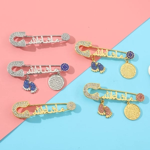 Detailed view of Mashallah baby feet brooches with crystals on pink and blue background