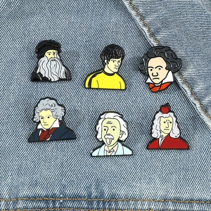 Set of 6 cartoon famous historical figure enamel pins on blue denim fabric background