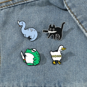 Detailweergave van grappige emaille pins met kat, kikker en gans op denim stof