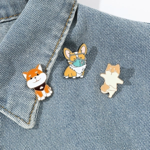 Detailed close-up of three cute enamel cartoon dog pins on blue denim fabric texture