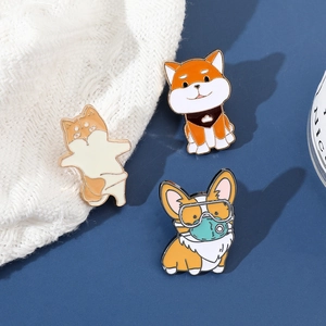 Detailed view of three cute enamel dog pins including Shiba Inu and Corgi styles on fabric