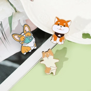 Close-up of enamel dog pins featuring Corgi and Shiba Inu designs on a green background