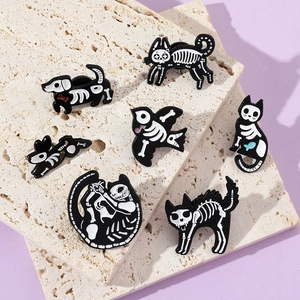 Detailed view of 7 black animal skeleton enamel pins arranged on light textured stone