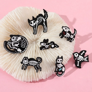 Detailed set of black and white enamel animal skeleton brooches on a pink display