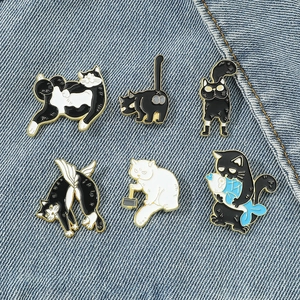 Set of six cute cartoon cat enamel pins with fish on a blue denim background