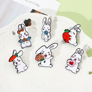 Makroaufnahme von sechs süßen Cartoon-Hasen-Emaille-Pins in einer weißen Keramikschale