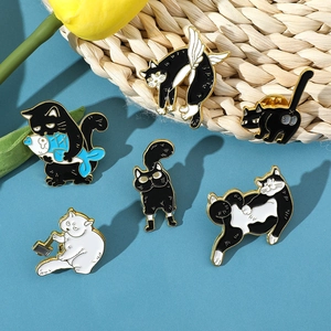Macro detail of cartoon cat enamel pins featuring black and white feline shapes on a blue base