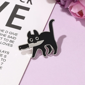 Détail d'un pin's émaillé de chat noir avec couteau sur un fond violet pastel