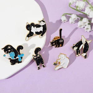 Flat lay of six cute cartoon cat enamel pins featuring kittens holding fish on a purple surface