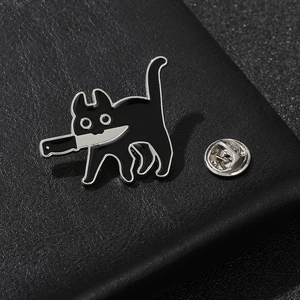 Gros plan du pin's chat noir émaillé avec couteau sur fond en cuir texturé noir