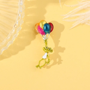 Détail d'un pin's grenouille mignonne avec ballons colorés sur fond jaune pastel
